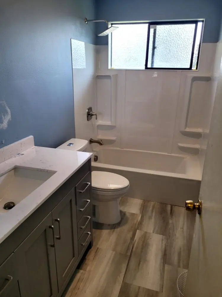 Finished bathroom remodel with a tiled tub surround and gray vanity